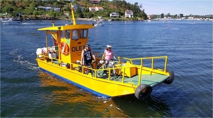 Yellow passenger ferry carrying cyclists across a broad estuary
